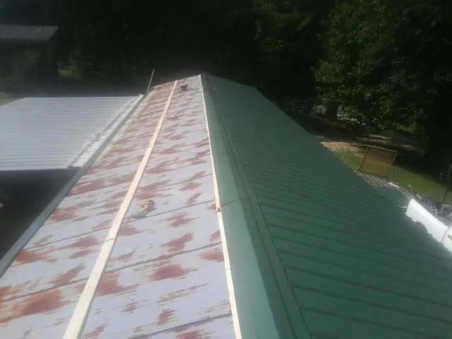 Old rusted panels beside newly installed green metal roofing — Wind Damage Roof Repair by Roofing Brothers in Hall