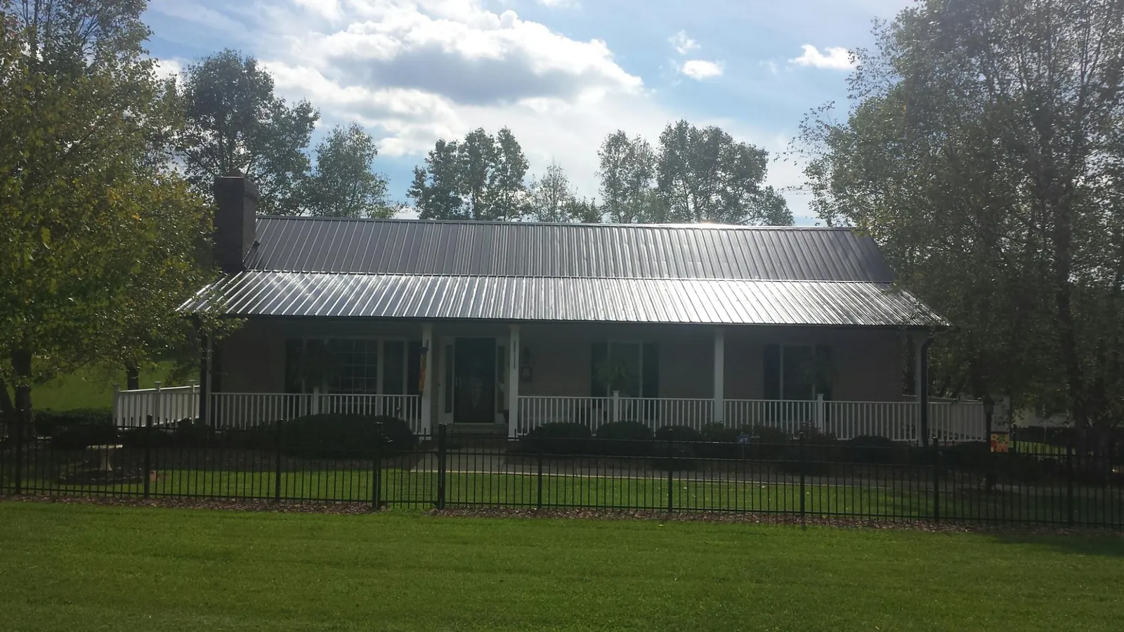 Gray metal roof on a brick ranch with a full width front porch — Gutter Guard Installation work by our crew in Hall