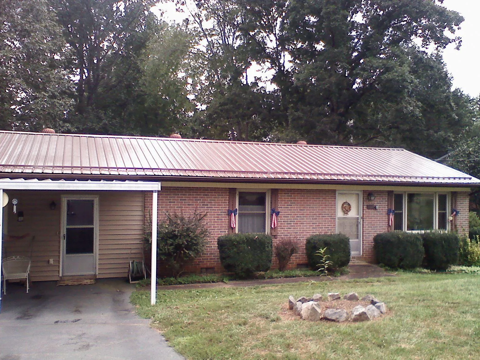 Bronze metal roof and carport on a brick ranch home — Roof Repair work by our crew in Hall